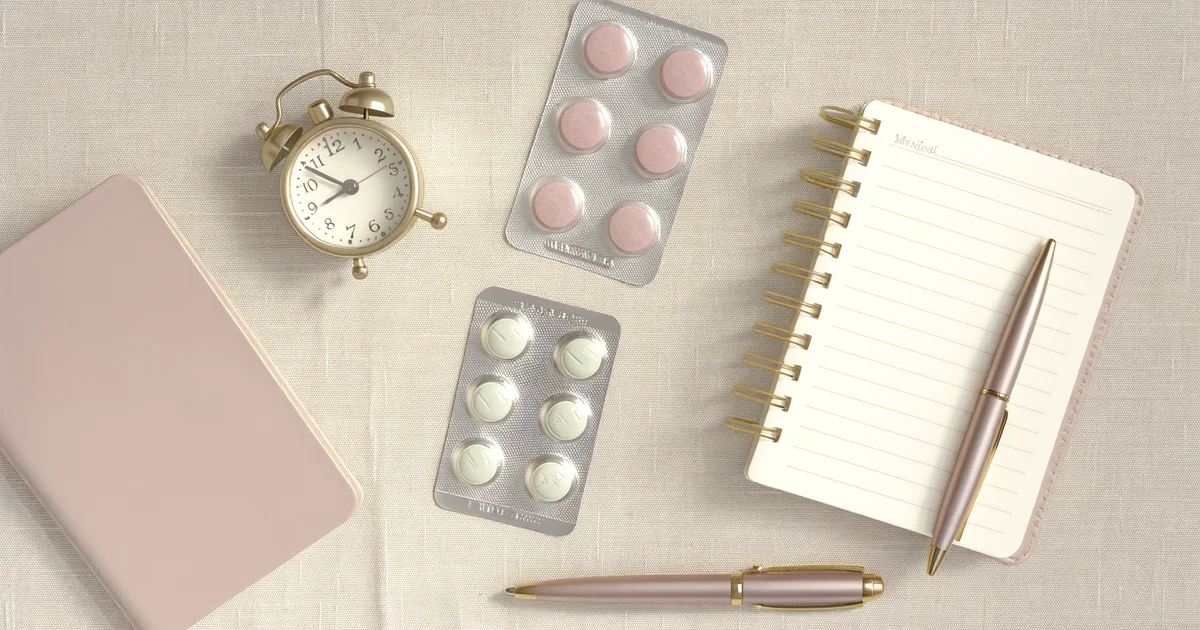 白いテーブルの上に置かれた錠剤と女性の手。緊急避妊薬・アフターピルのイメージ